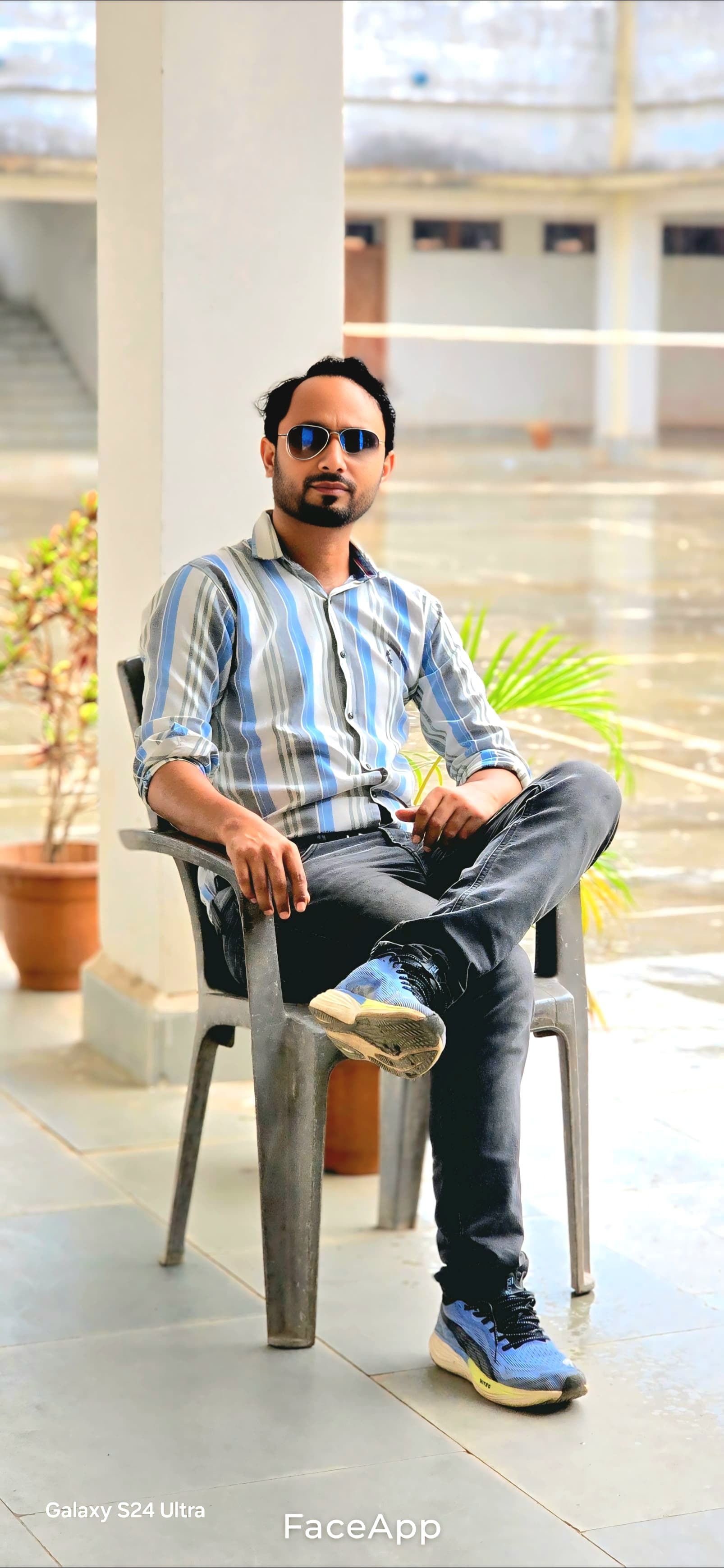 Professional portrait seated in institutional corridor wearing striped shirt - Formal academic setting