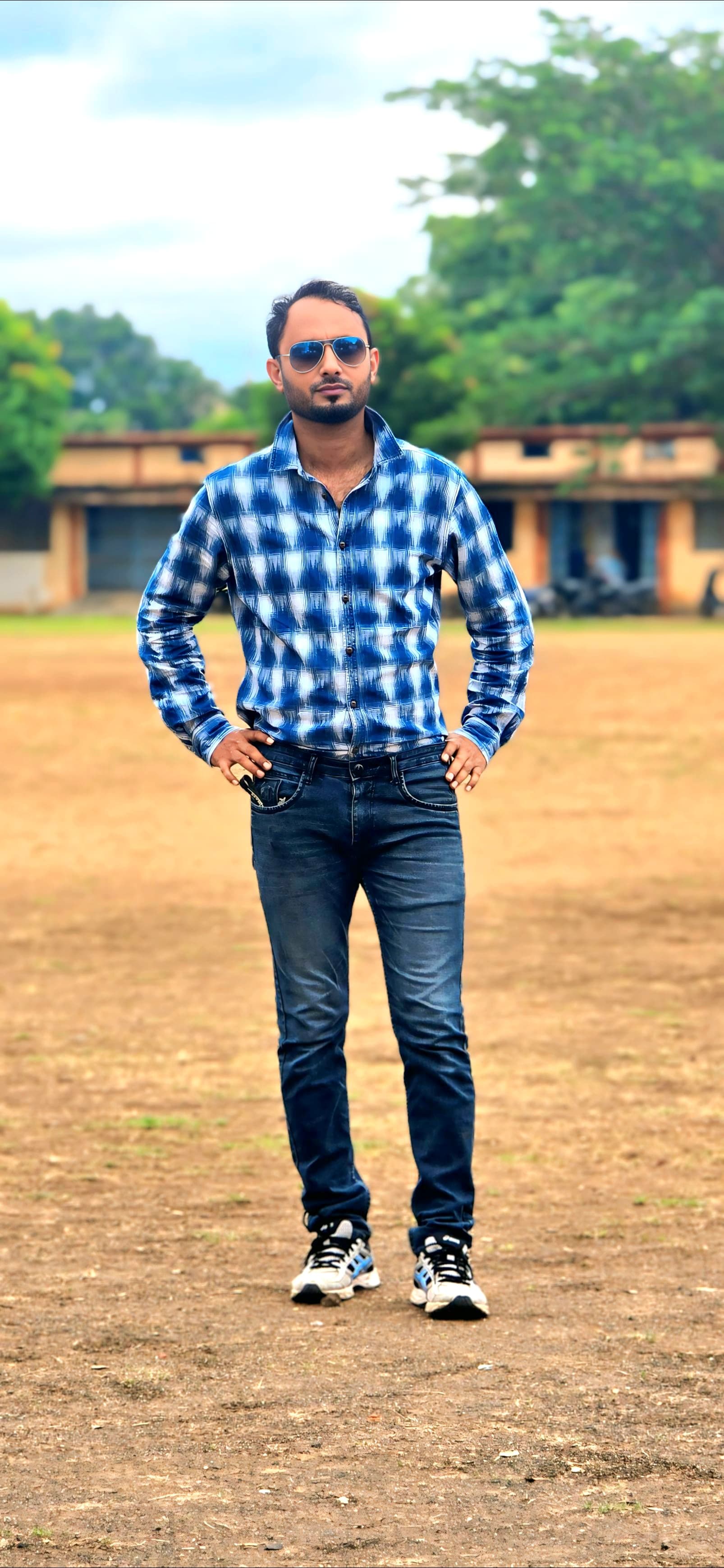 Professional field portrait in blue checkered shirt - Outdoor sports field setting with natural lighting