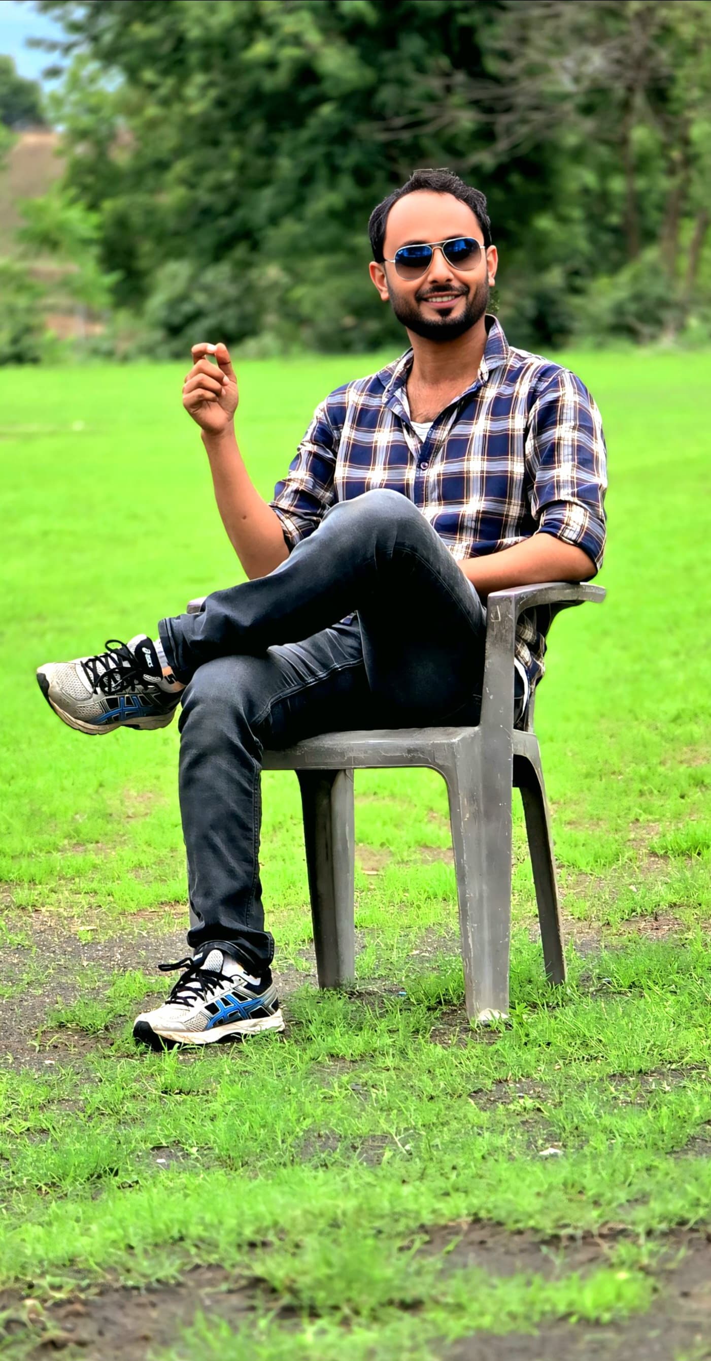 Casual outdoor portrait seated on lawn chair in plaid shirt - Relaxed campus environment setting
