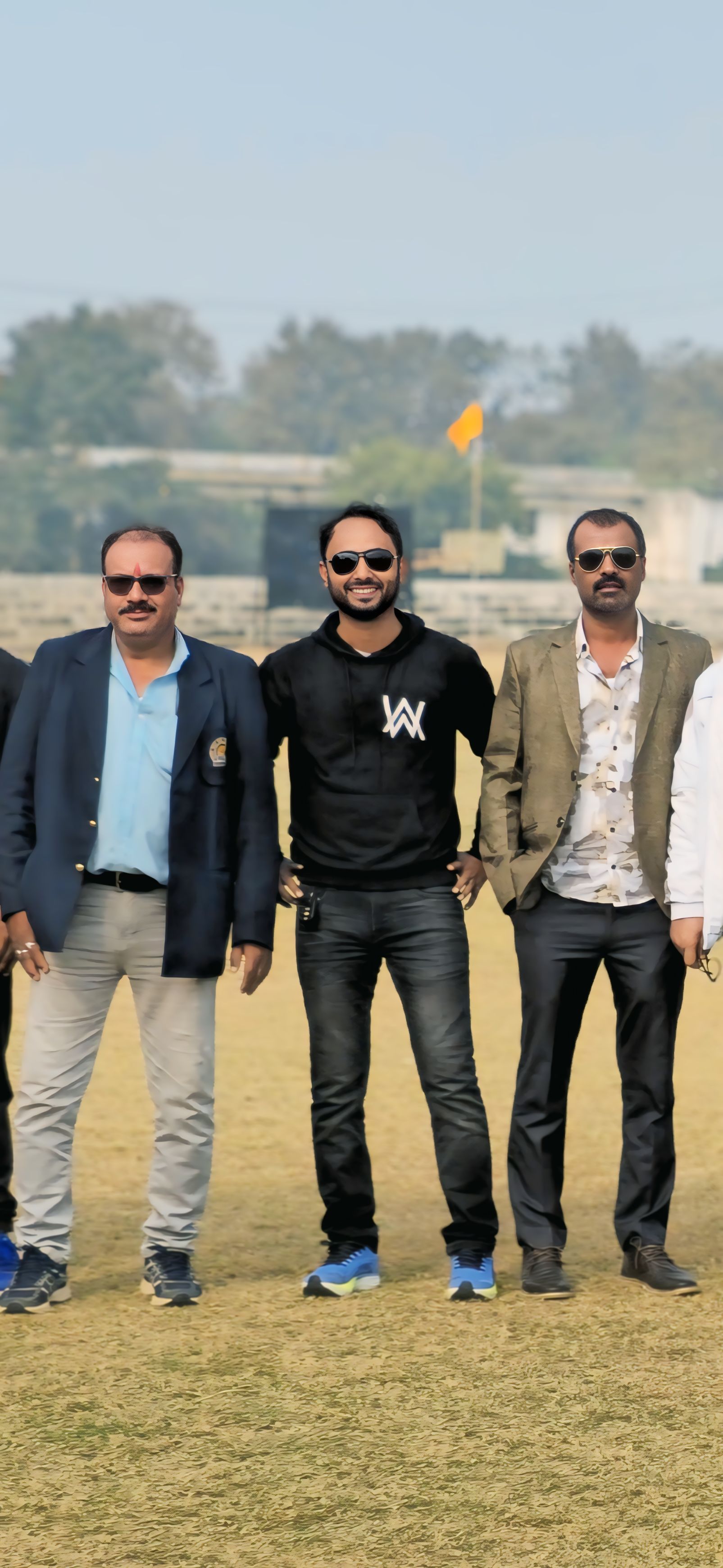 Outdoor sports crew group photo with black hoodie in center - Team coordination in natural outdoor setting